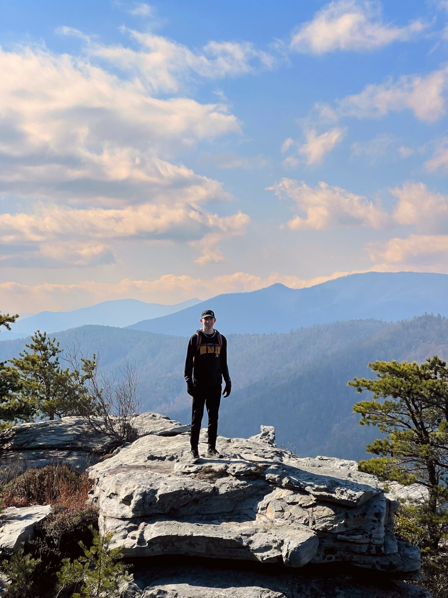 Oliver standing on a rocky overlook in the mountains